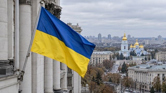 Kiev şehir manzarası önünde bir binadan sarkan Ukrayna bayrağı